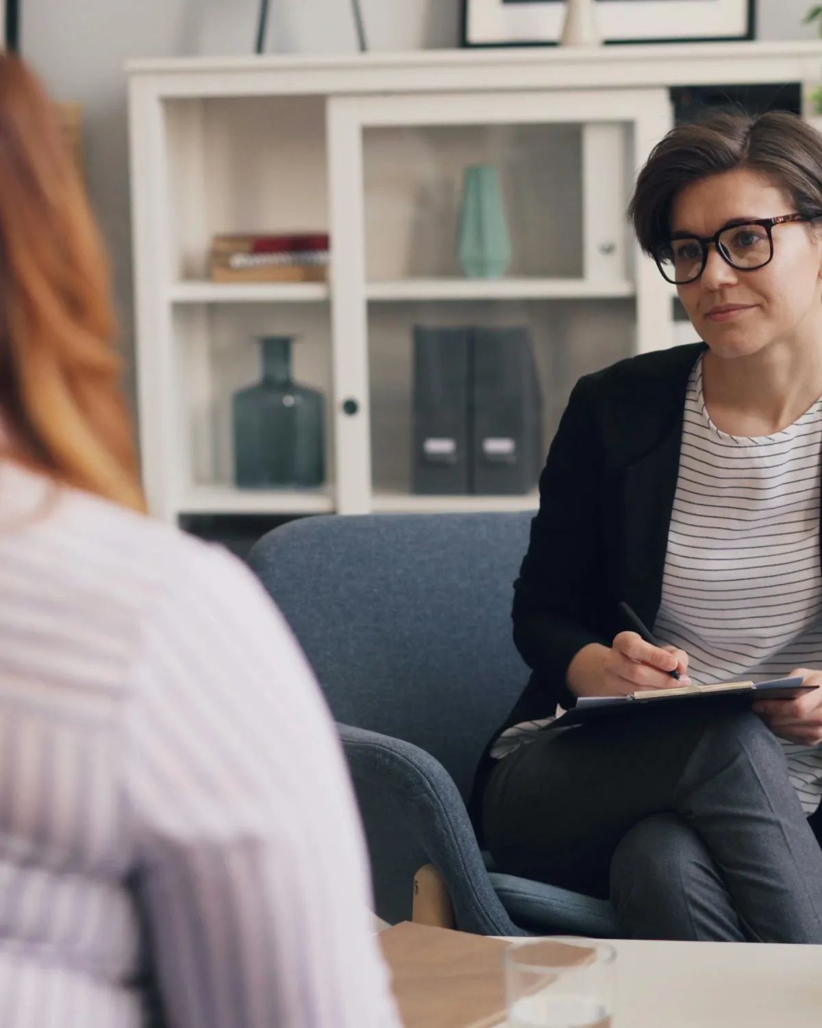 Therapist with clipboard conducting a Cognitive Behavioral Therapy session